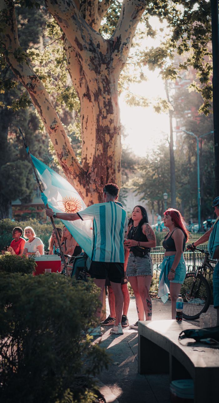 Services Group of people celebrating in a park with an Argentinian flag during daytime.